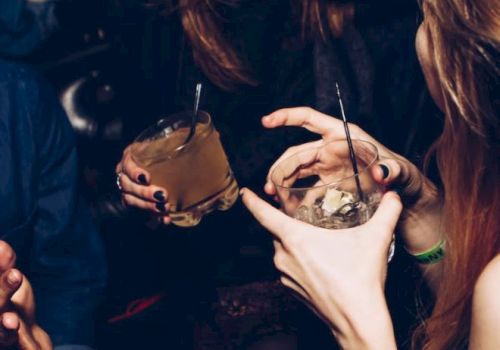 People are sitting together, holding drinks and interacting in a lively setting.