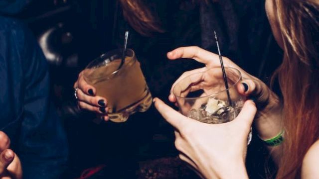 People are sitting together, holding drinks and interacting in a lively setting.