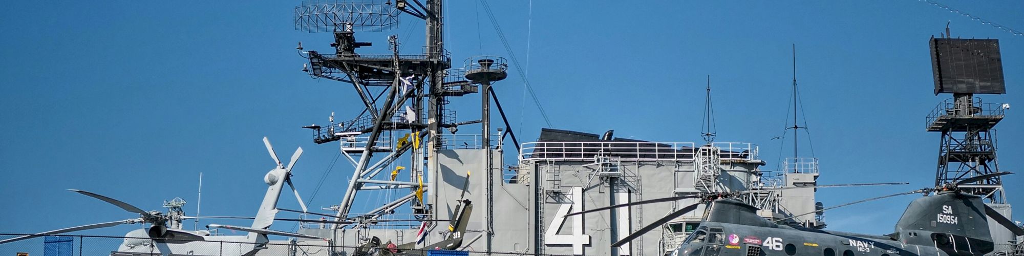 The image shows a naval warship with the number 41, featuring a helicopter on its deck and an American flag waving above.