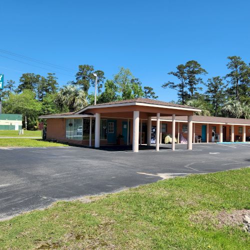 The image shows a single-story motel with a sign reading 