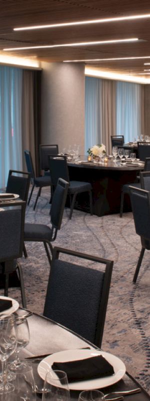 This image shows an elegantly decorated banquet room with round tables, chairs, and place settings, ready for an event or dinner.