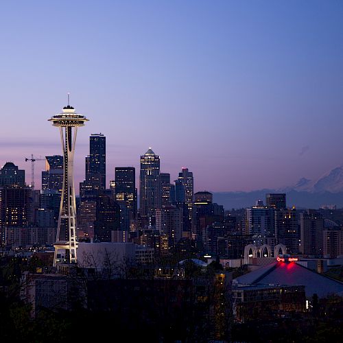 This image shows the Seattle skyline at dusk, featuring the Space Needle, city buildings, and Mount Rainier in the background.